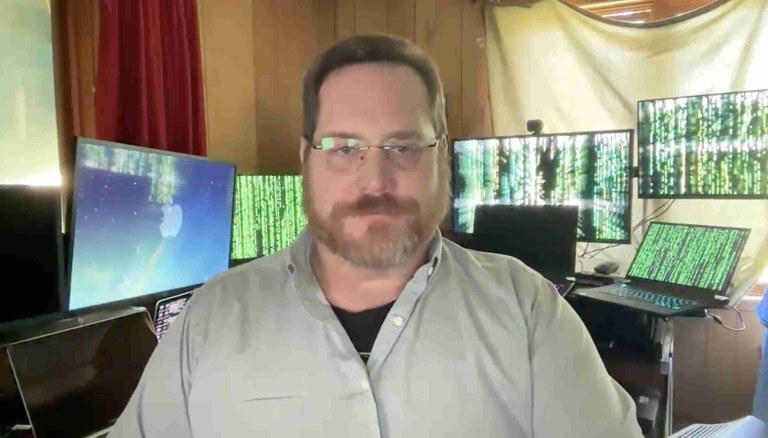 Hawke Robinson in his Home Office with some of his computers in the background running with The Matrix various screensavers.